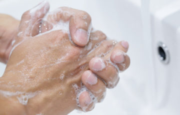 Händer tvättas i handfat under rinnande vatten