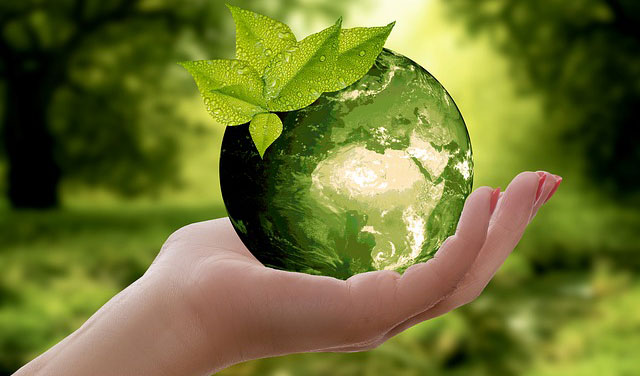 Grön jordglob och klimatsymbol i hand