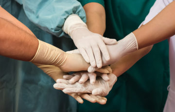 Sex läkare som lägger ihop händerna för att känna gemenskap. SYLF 100 år.