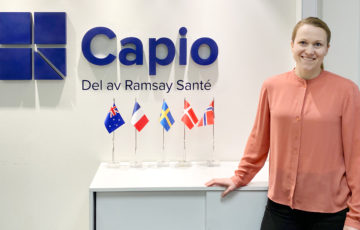 Lovisa Backemar står framför en vägg med Capios logotyp i blått.