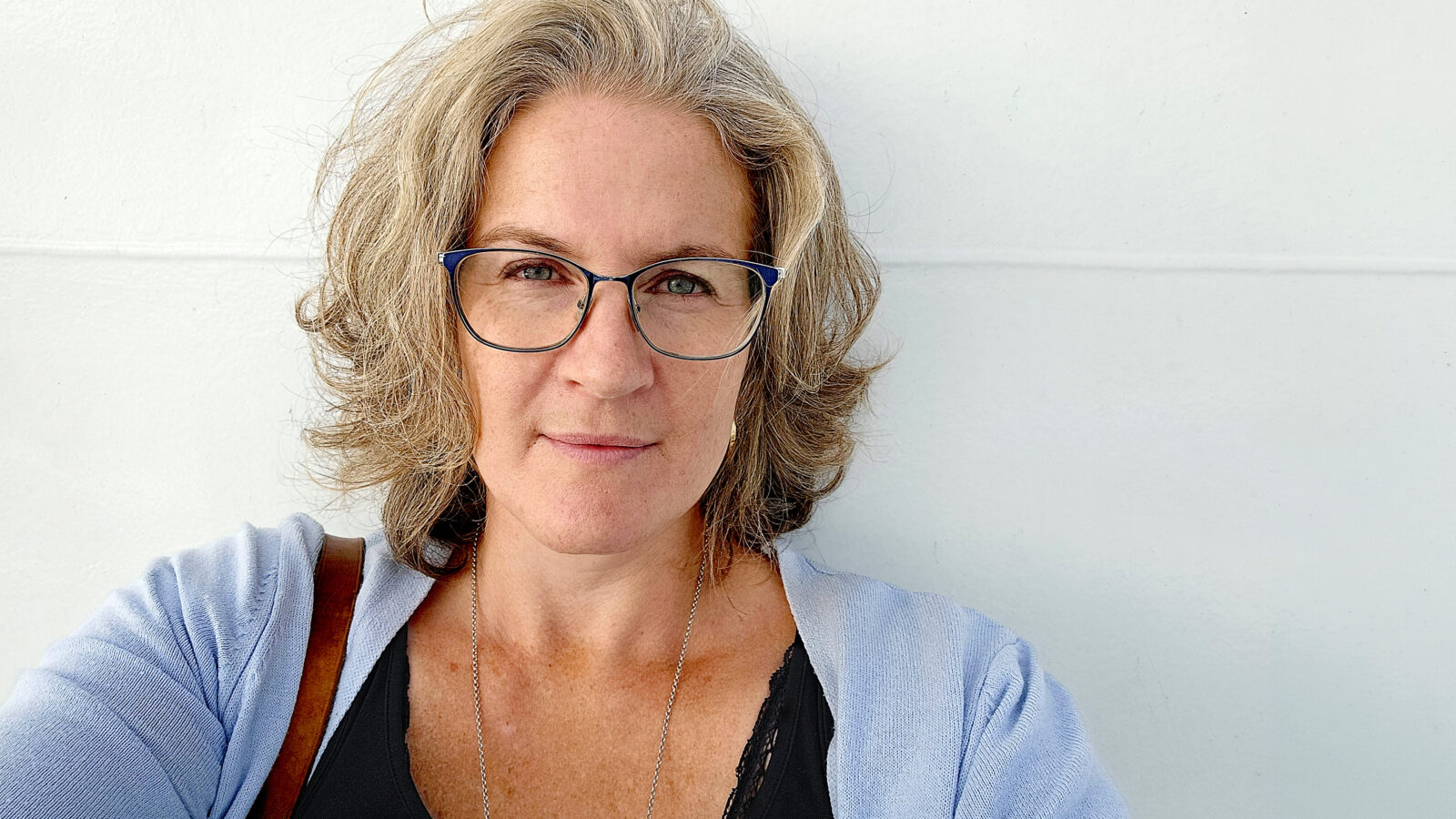 Eva Mathiasson-Rinblad fotograferad framför en vit vägg.