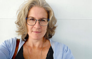 Eva Mathiasson-Rinblad fotograferad framför en vit vägg.